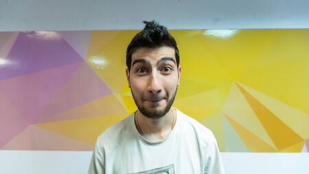 The black-haired young guy portrait on a colorful polygonal backgroundの写真素材