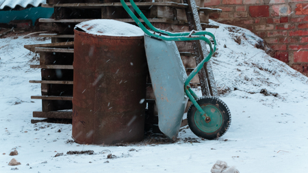 Cart rusty barrel and a stack of wooden pallets in the winter near the barnの写真素材
