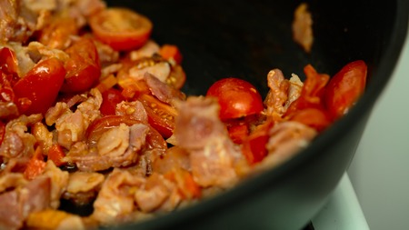 tomatoes bacon onion carrots in a pan closeupの写真素材