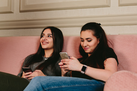 girls on the couch with smartphones. Studio horizontal portraitの写真素材