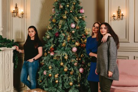 Three beautiful young girls near the Christmas tree. Studio horizontal portraitの写真素材