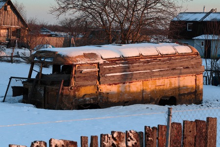 Old rusty and collapsed bus shrouded in snow. Photo in the daytime.の写真素材