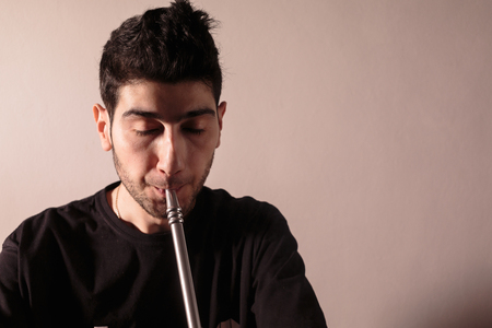 Young man smoking a hookah. Close up photo.