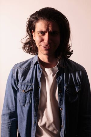Beautiful man with long hair in a denim shirt. Nice photo.