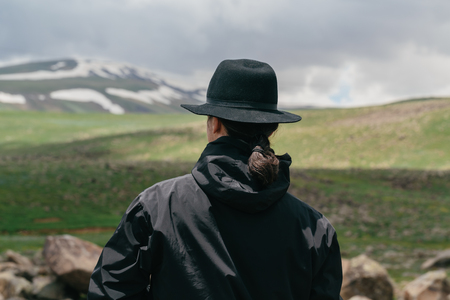 Fashionable man in a hat against the background of the Armenian mountains. Back view.の写真素材