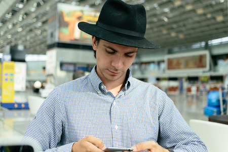 Fashionable man in a hat uses his smartphone. Front view.の写真素材