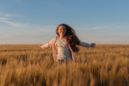 Teen girl in a yellow field. Photo in the daytime.の写真素材