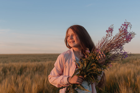 Teen girl in a field with flowers.の写真素材