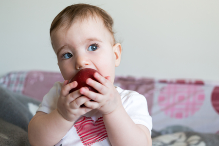 Small child eats a red apple at home closeup.の写真素材
