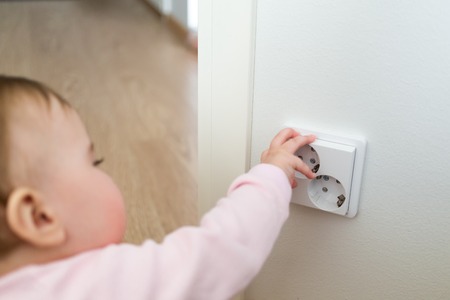 Small child touches an electrical outlet at home. Safety of childrenの写真素材