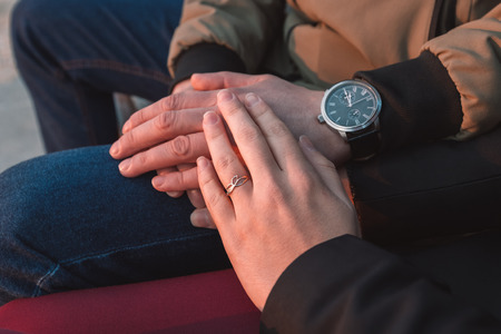 hands of a young loving couple close-up in the fall.の写真素材