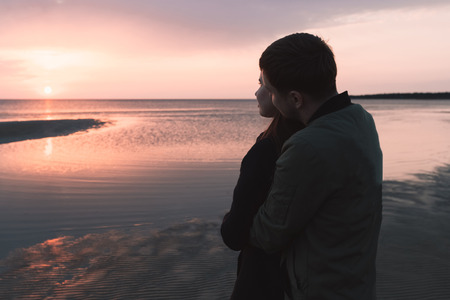 young loving couple watching the sunset at the sea in autumn.の写真素材