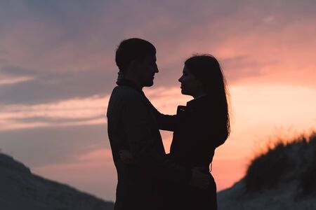 young couple hugging by the sea at sunset in autumn close-upの写真素材