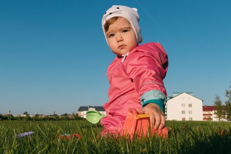 small child playing sitting on a lawn in autumn.の写真素材