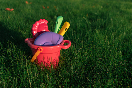 childrens colorful toys in a bucket on a green lawn.の写真素材