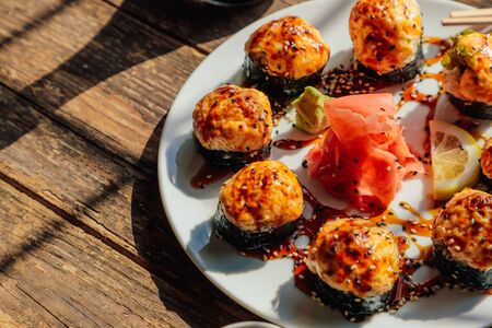 baked Japanese rolls in a white plate on an old wooden tableの写真素材