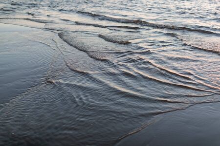 photo of the tide of water on a sandy beach
