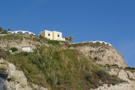 building on a hill against a blue sky in the daytimeの写真素材
