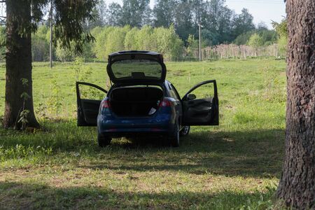 car with open doors and a luggage compartment in nature in the shadeの写真素材