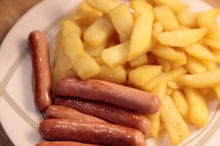 fried potatoes with fried sausages on a plate close upの写真素材