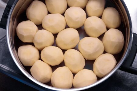 peeled potatoes in a saucepan with water close-upの写真素材