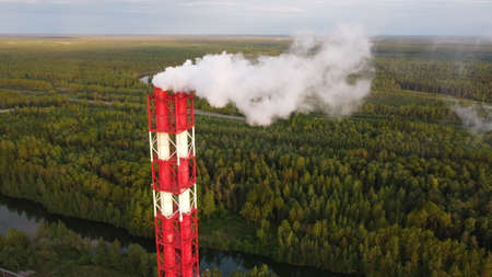 Air pollution by smoke coming out of factory chimneys. Birds-eye view of the industrial zone in the...