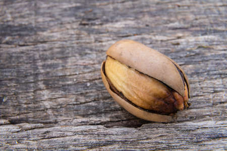 Macro photo of an acorn with a cracked shell on a wooden backgroundの写真素材