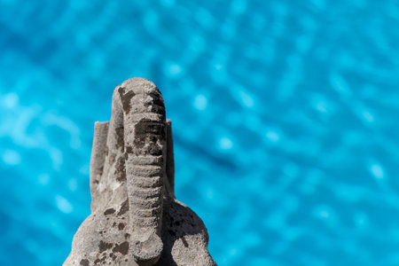 A stone sculpture of an elephant head over a pool of turquoise blue waterの写真素材