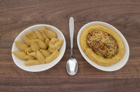 A combination of two types of mustard in a white bowl on a wooden base and served in different ways