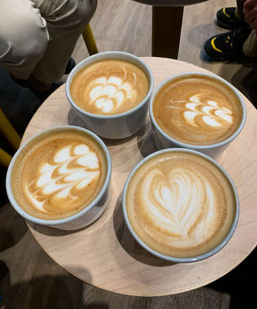 Four cups of cappuccino with decorations on milk foam