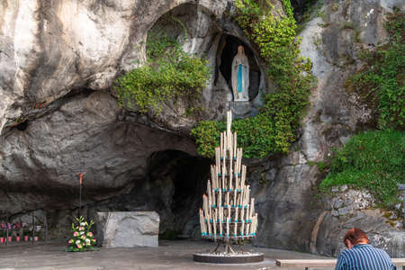 Lourdes, France - August 28, 2021: Woman praying in front of the cave of apparitions of holy Mary in Lourdesのeditorial素材