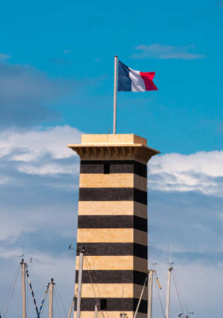 Deauville, France - August 6, 2021: The Marina Port and its tower with french flag in Trouville,...