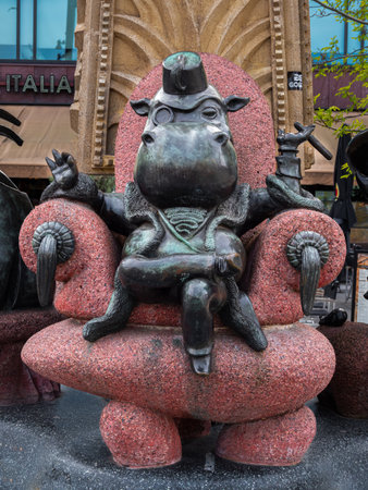 Rotterdam, Netherlands - April 28, 2022: A funny modern sculpture of a sitting businessman with the head of a hippopotamus, with his legs crossed and a cigar in his hand.のeditorial素材