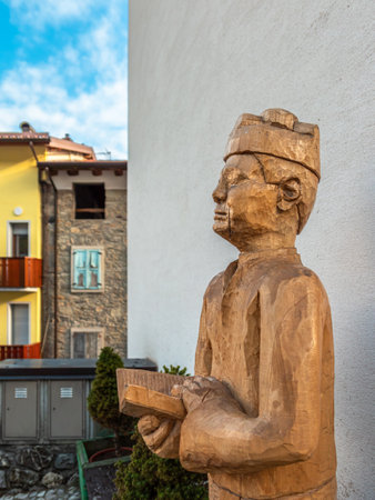 Sutrio, Italy - December 29, 2022: a Wooden sculpture of a village pastor with an open bookのeditorial素材