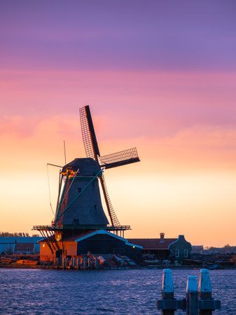The picturesque Zaanse Schans of the Netherlands, with an iconic windmill against a dreamy sunset sky and tranquil sea.の写真素材