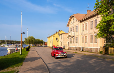 Amal, Sweden - May 25, 2023: A red vintage Volvo car drives along the street of the old town of Amal and next to the marinaのeditorial素材