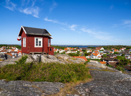 Red swedish wooden cottage on the top of the hill and a view at the cityscape of the island Vrango in Sweden, near the Gothenburgの写真素材