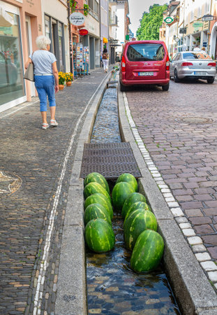 Freiburg im Breisgau, Germany - July 6, 2023: A fruit and vegetable vendor cools watermelons in a sunny day in a city sewerのeditorial素材