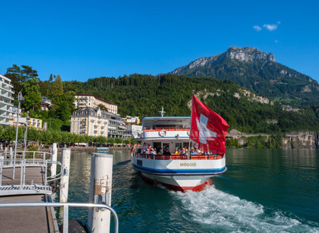 Brunnen, Switzerland - September 6, 2023: The tourist ship Weggis, with waving Swiss flag, leaves the harbor in Brunnen, canton Schwyzのeditorial素材