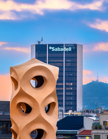 Barcelona, Spain - October 7, 2023: Headquarters of the bank Sabadell in Barcelona, Catalonia, Spain. A sculpture on the roof of the house Pedrera in foregroundのeditorial素材