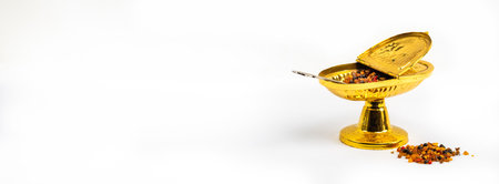 Golden incense container with open cover and grains of incense
