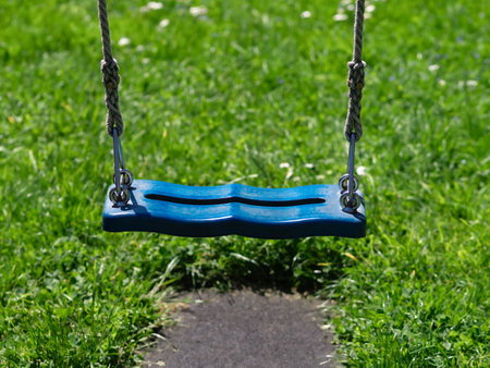 Tranquil blue swing in park. Symbolizes relaxation and childhood joy. Llifestyle and leisure...