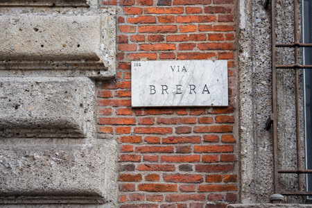 A street sign reading Via Brera, Milan, mounted on a brick wall, showcasing urban architecture