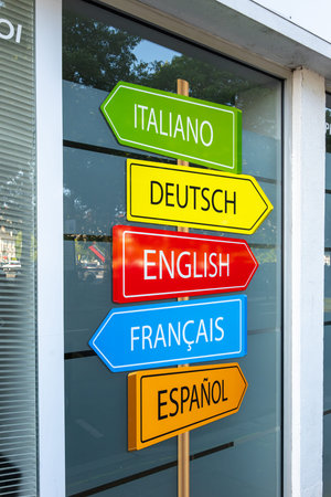 Caen, France - August 5, 2025: Colorful multilingual signpost with language names in a window...