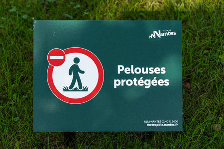 Nantes, France - August 5, 2025: Sign on grass prohibiting walking, with text in French.のeditorial素材