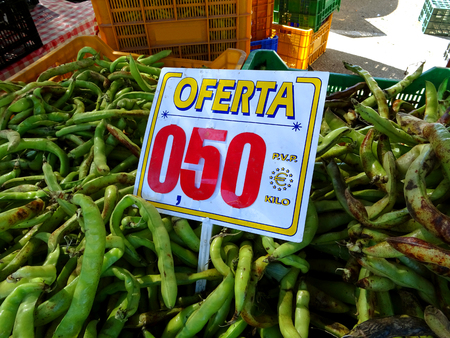 Green broad beans stand in the market stall with price tagの写真素材