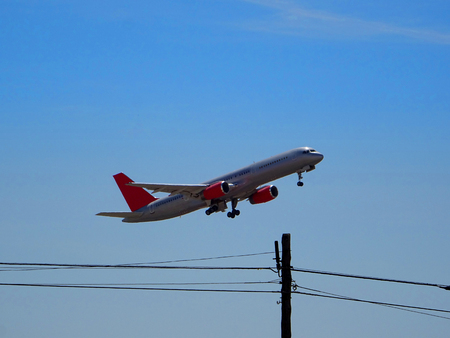Commercial airplane taking off with view of telephone wiresの写真素材