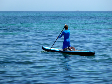 young man practicing paddle on the beach with calm seaの写真素材