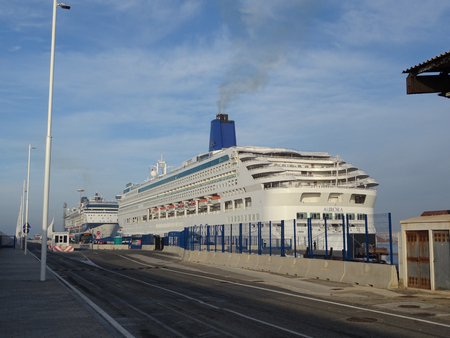 cruise ship at the dock unloading passengers early in the morning with bus shuttles ready to visit the cityの写真素材