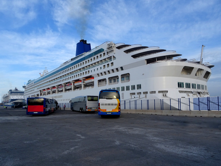 cruise ship at the dock unloading passengers early in the morning with bus shuttles ready to visit the cityの写真素材